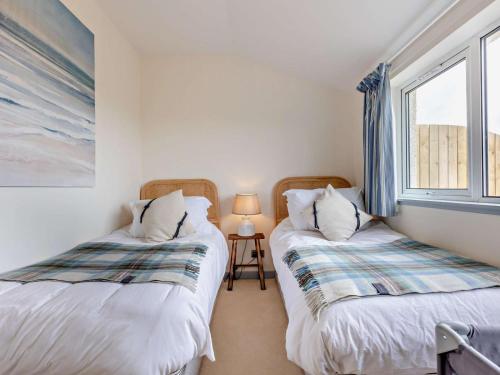 two twin beds in a room with a window at 3 Bed in Arbroath oc-90784 in Inverkeilor