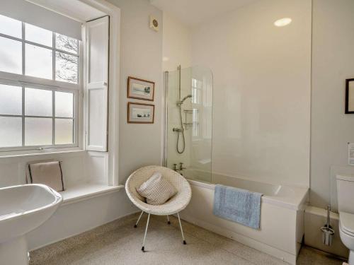 a bathroom with a tub and a chair and a sink at 4 Bed in Penrith oc-94247 in Greystoke