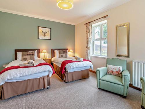 a bedroom with two beds and a chair and a window at 2 Bed in Brechin oc-ca300 in Edzell