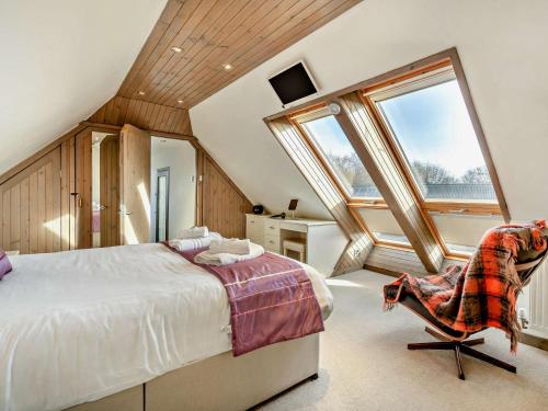 a bedroom with a bed and a chair and windows at 3 Bed in Cupar oc-54394 in Peat Inn 