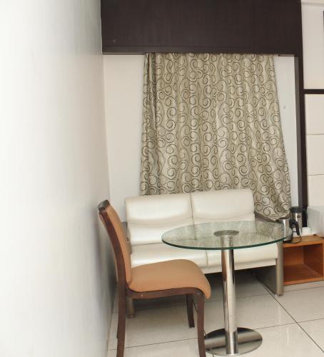 a dining room with a glass table and a chair at Hotel Royal Shelter in Vapi