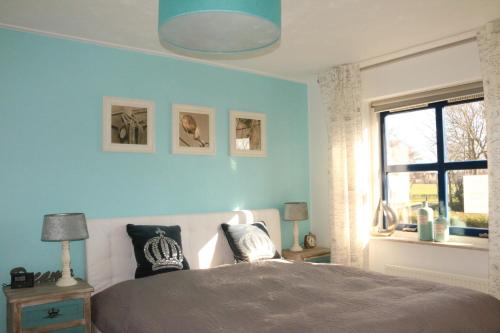 Dormitorio azul con cama y ventana en Ferienhaus Ooghduyne 33 en Julianadorp
