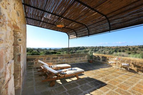 an outdoor patio with lounge chairs and a roof at Masseria Fano Relais & Wine in Salve