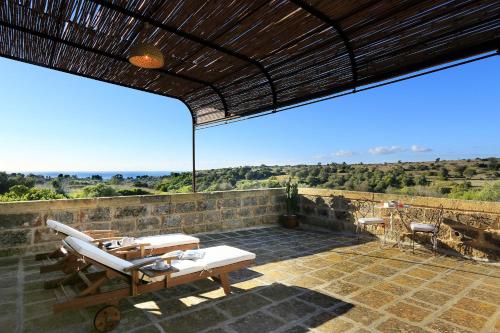 a patio with chairs and tables on a stone wall at Masseria Fano Relais & Wine in Salve