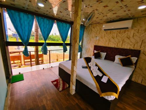 a bedroom with a bed and a large window at Sheoak Retreat Tajpur in Tajpur