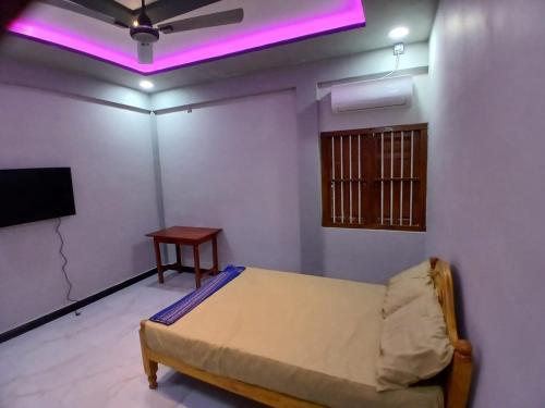 a room with a bed and a tv and a table at AR villa in Jaffna