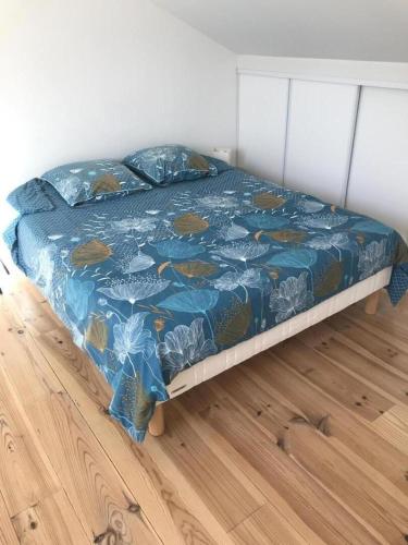 a bed with a blue comforter and pillows on it at Le loft 2 in Vouneuil-sous-Biard