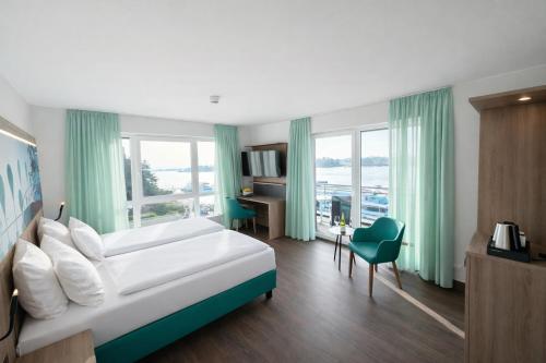 a hotel room with a bed and a desk and window at Hotel Rheinpark Rees in Rees