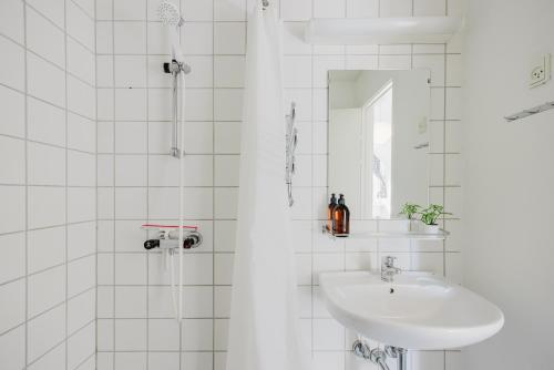 a white bathroom with a sink and a mirror at Nomad City Hotel - Odense in Odense
