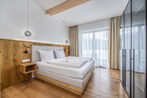 a bedroom with a white bed and a large window at Schmuckstück Ferienapartments Bodenmais inkl aktivCARD in Bodenmais