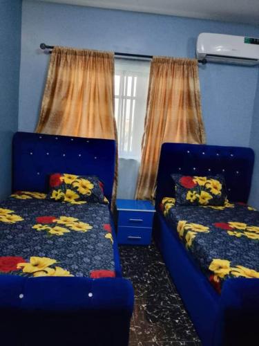 a blue room with two beds and curtains at Aduniniyi 7 Shines in Igando