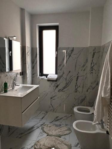 a bathroom with a sink and a toilet and a window at Hij Apartaments in Rădăuţi