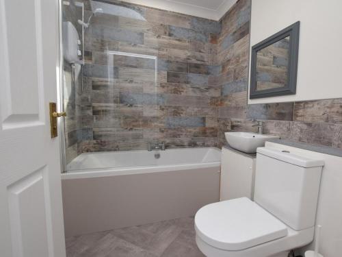 a bathroom with a toilet and a tub and a sink at 1 Bed in Biggar oc-82923 in Biggar