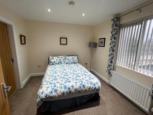 a bedroom with a bed with a blue comforter and a window at Copperbeech Farm Cottages in Maze