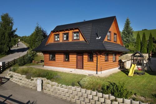 a wooden house with a black roof and a playground at Zrub pod Roháčmi in Zuberec