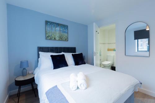 a blue bedroom with a white bed with two towels at Spacious City Centre Apartment with Balcony in Wolverhampton