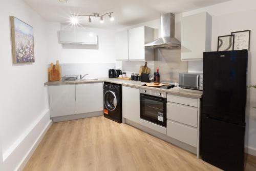 a kitchen with white cabinets and a black refrigerator at Spacious City Centre Apartment with Balcony in Wolverhampton
