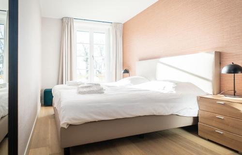a bedroom with a large white bed and a window at R-1 Hoeve Holland in De Cocksdorp