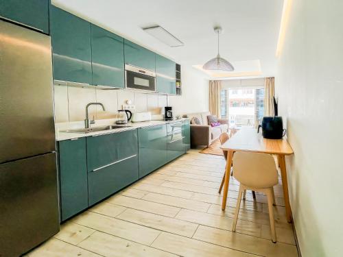 a kitchen with green cabinets and a wooden table at Casa Arno - Lovely Renovated Apartment In Playa De Mogan in Puerto de Mogán
