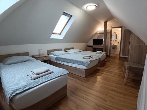 a bedroom with two beds and a window at The Corner House Panzió in Tata