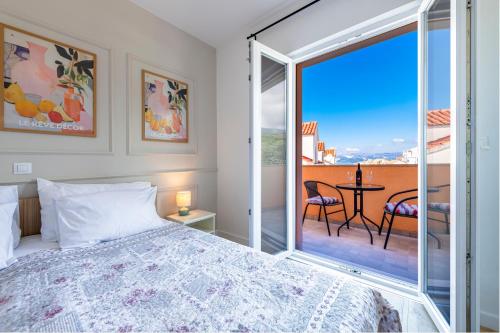 a bedroom with a bed and a balcony with a table at Apartments Mrkan 2 in Cavtat