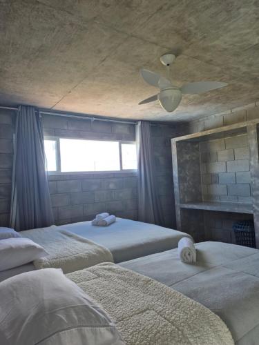 a bedroom with three beds and a ceiling fan at Casa Concept in Mucugê