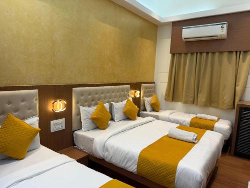 a bedroom with two beds with yellow and white pillows at Hotel Sweet Inn in Mumbai