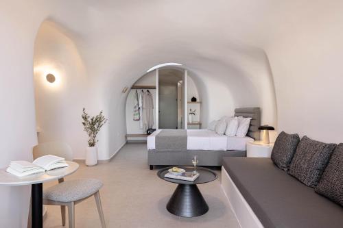 a hotel room with a bed and a couch at Filomare Oia Suites in Oia