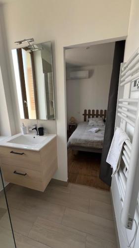 a bathroom with a sink and a mirror and a bed at Chambres d'Hôtes de Marchet in Auvillar