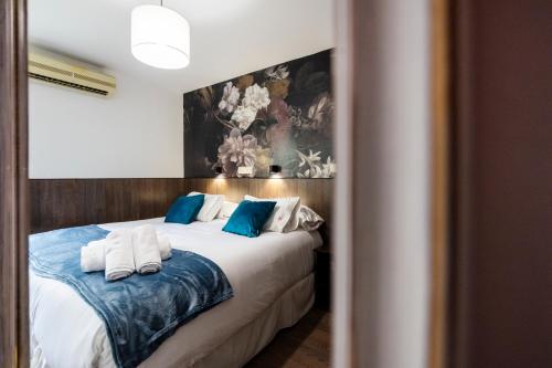 a bedroom with a bed with blue and white pillows at Veracruz Boutique Puerta del Sol in Madrid
