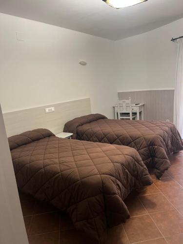 a bedroom with two beds and a table and a chair at Hostal Hueso in Trujillo
