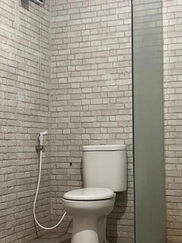 a bathroom with a toilet and a brick wall at PaddyView Hostel in Banyuwangi
