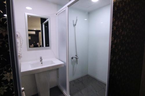 a white bathroom with a sink and a shower at Hotel 6 - Wannien in Taipei