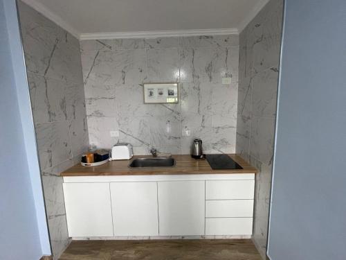 a kitchen with a sink and a marble wall at El Viejo Albergue in Luján