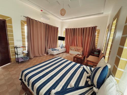 a bedroom with a large bed with a striped blanket at RyadIbou in Essaouira