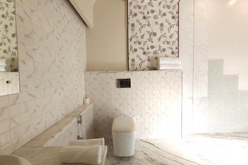 a white bathroom with a toilet and a mirror at Shlaka Farms in Jaipur