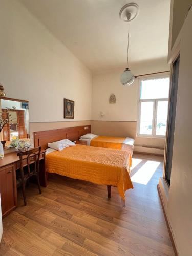 a bedroom with two beds and a desk and a window at Hotel Acropolis in Kavála