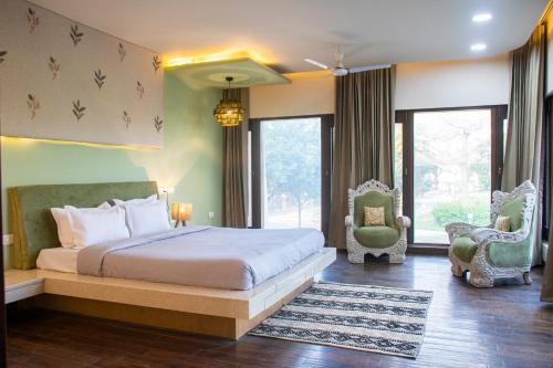a bedroom with a bed and a chair and windows at Shlaka Farms in Jaipur