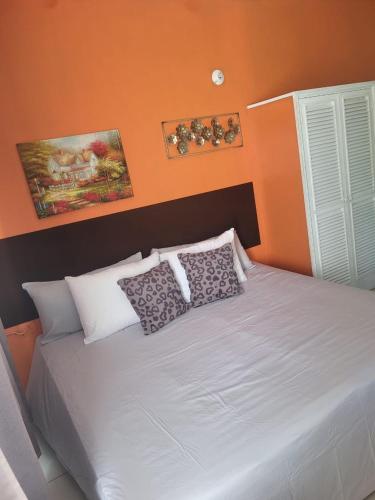 a bedroom with a white bed with an orange wall at Mar Paraiso in Ocho Rios