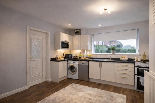 a kitchen with white cabinets and a window at Taylor House - Durham in Bearpark