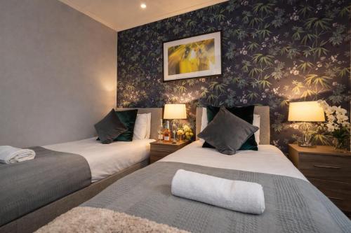 two beds in a room with floral wallpaper at Taylor House - Durham in Bearpark