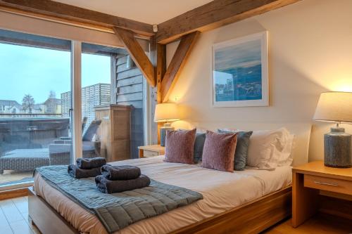 a bedroom with a large bed with pillows on it at Lakeside Cotswolds Retreat with Private Hot Tub set on Lower Mill Estate in Somerford Keynes