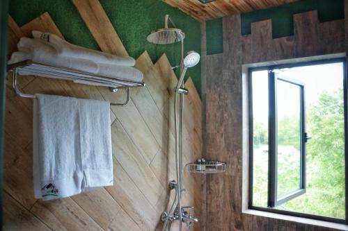 łazienka z prysznicem, ręcznikami i oknem w obiekcie Waian NO.5 Inn w mieście Deqing