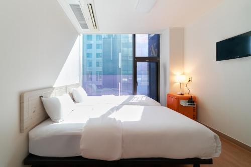 a bedroom with a large white bed and a window at K9 Myeongdong Hotel in Seoul
