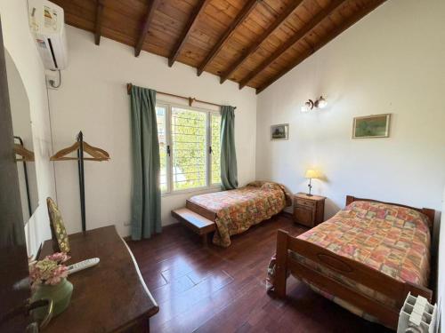 a bedroom with two beds and a table and a window at VALERIA 4 Ambientes in Valeria del Mar