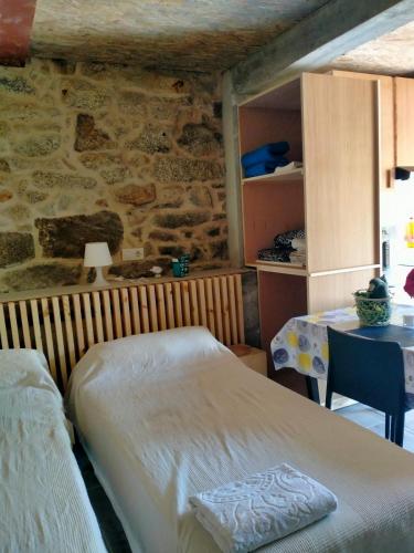 a bedroom with two beds and a stone wall at Vía Láctea Costa da Morte in Dumbría