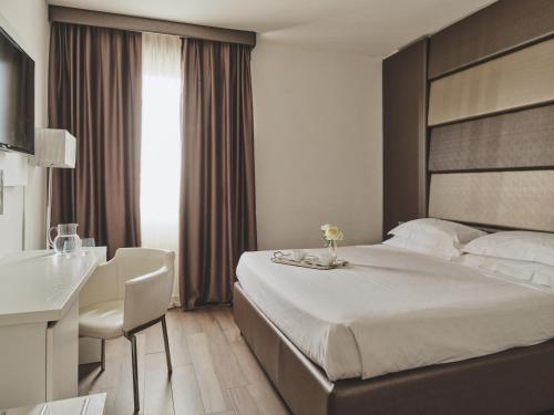 a hotel room with a large bed and a desk at Toscana Ambassador in Poggibonsi