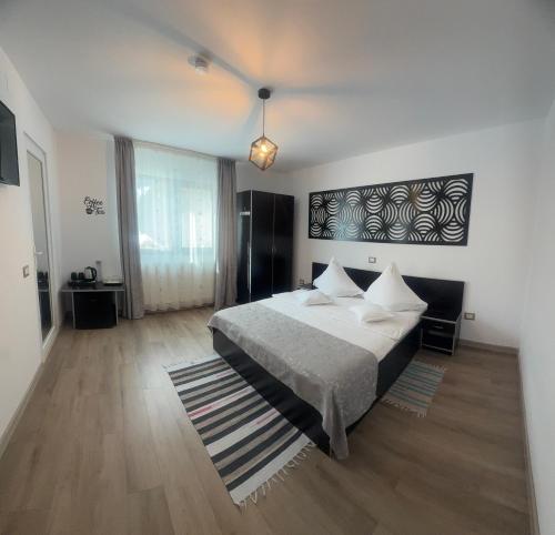 a bedroom with a bed with white sheets and pillows at Pensiunea Emage Moieciu in Moieciu de Sus