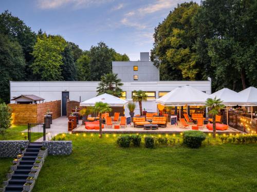 an outdoor patio with orange chairs and umbrellas at Sunday Hotel Bielefeld Johannisberg in Bielefeld