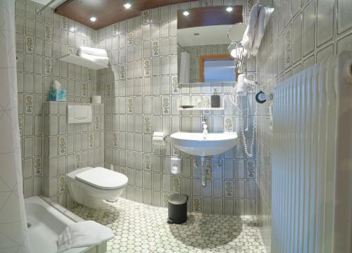 a bathroom with a sink and a toilet and a tub at Kräuterhex' Reutin in Alpirsbach